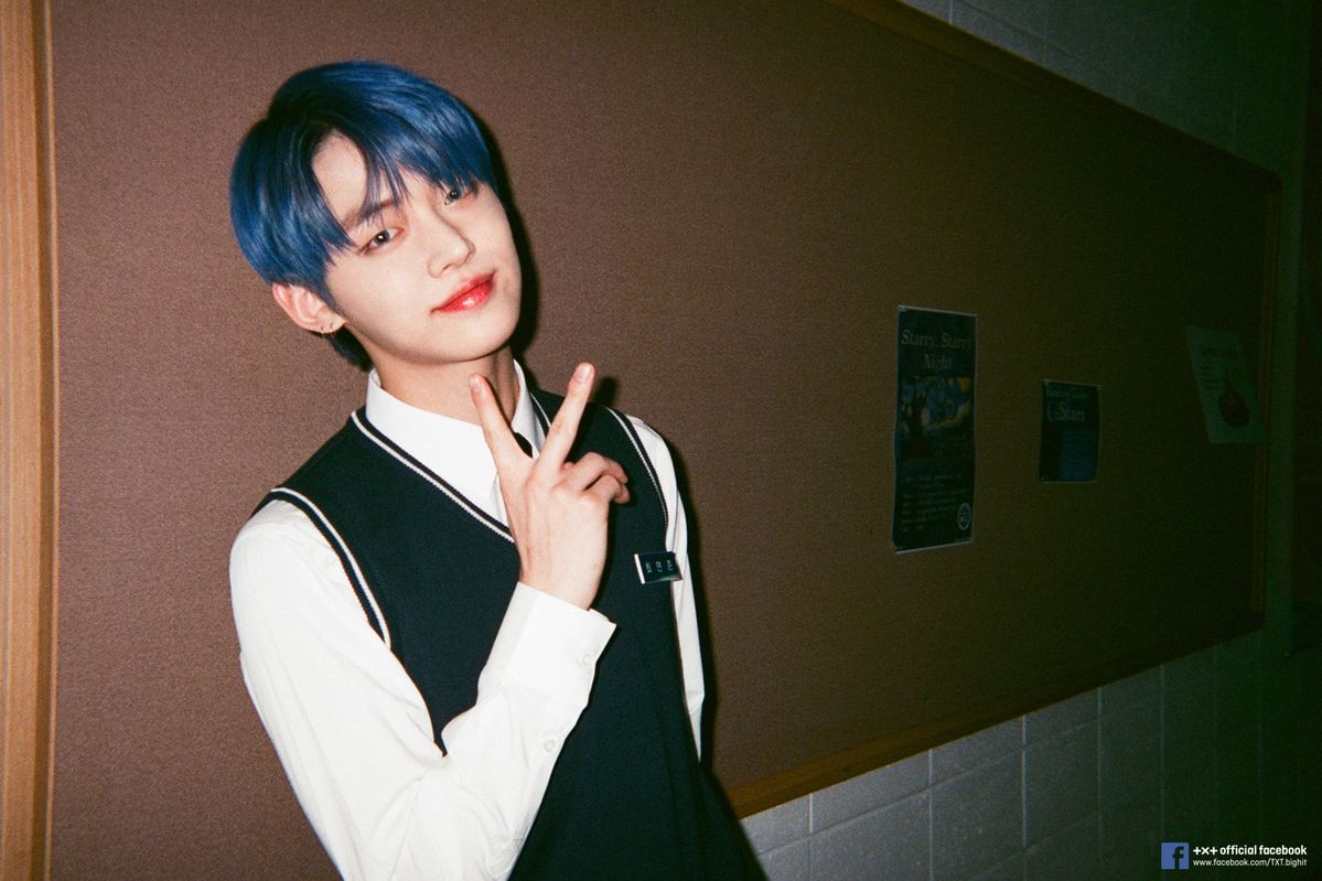 Yeonjun from TXT 
  laying back on a blackboard